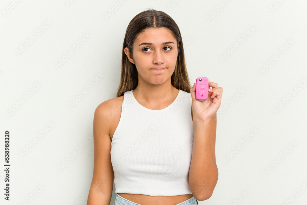 Young indian woman holding an electronic pink car keys confused, feels doubtful and unsure. Young indian woman holding an electronic pink car keys confused, feels doubtful and unsure.