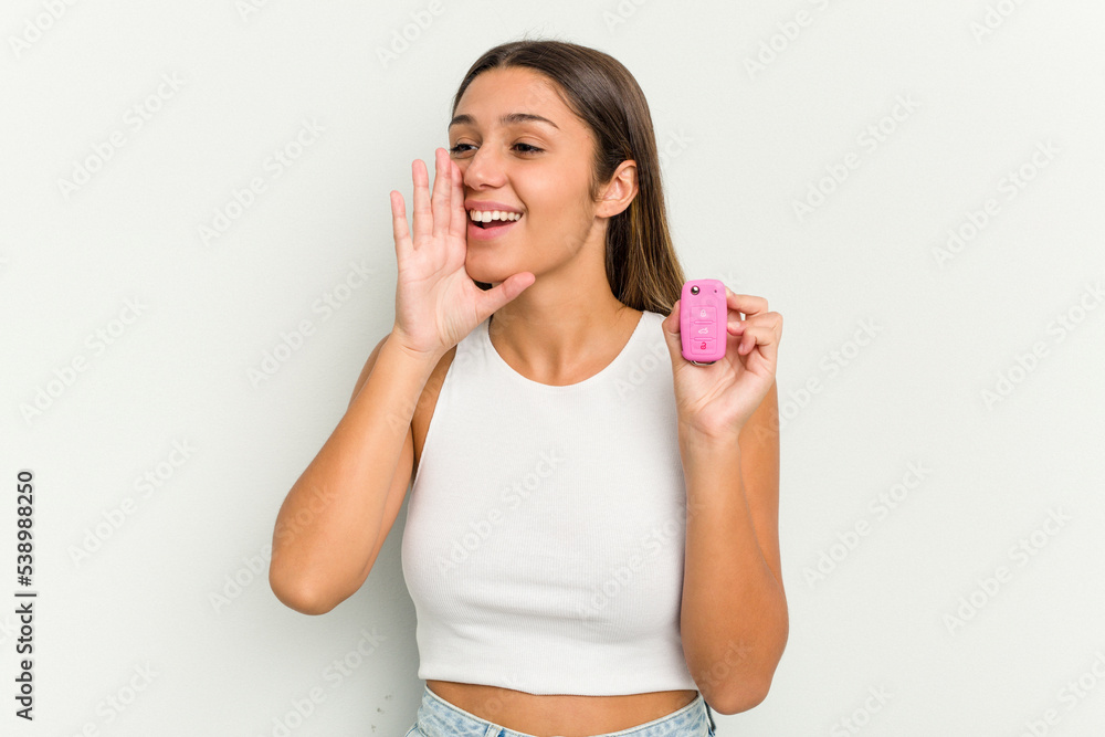 Young indian woman holding an electronic pink car keys shouting and holding palm near opened mouth. Young indian woman holding an electronic pink car keys shouting and holding palm near opened mouth.