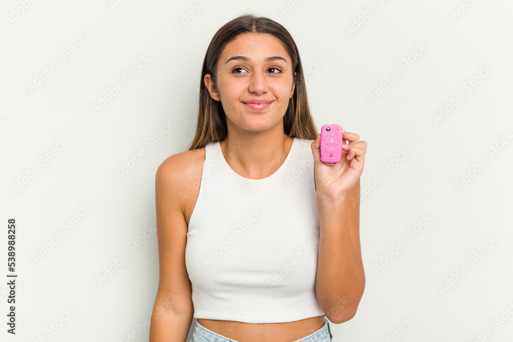 Young indian woman holding an electronic pink car keys dreaming of achieving goals and purposes Young indian woman holding an electronic pink car keys dreaming of achieving goals and purposes