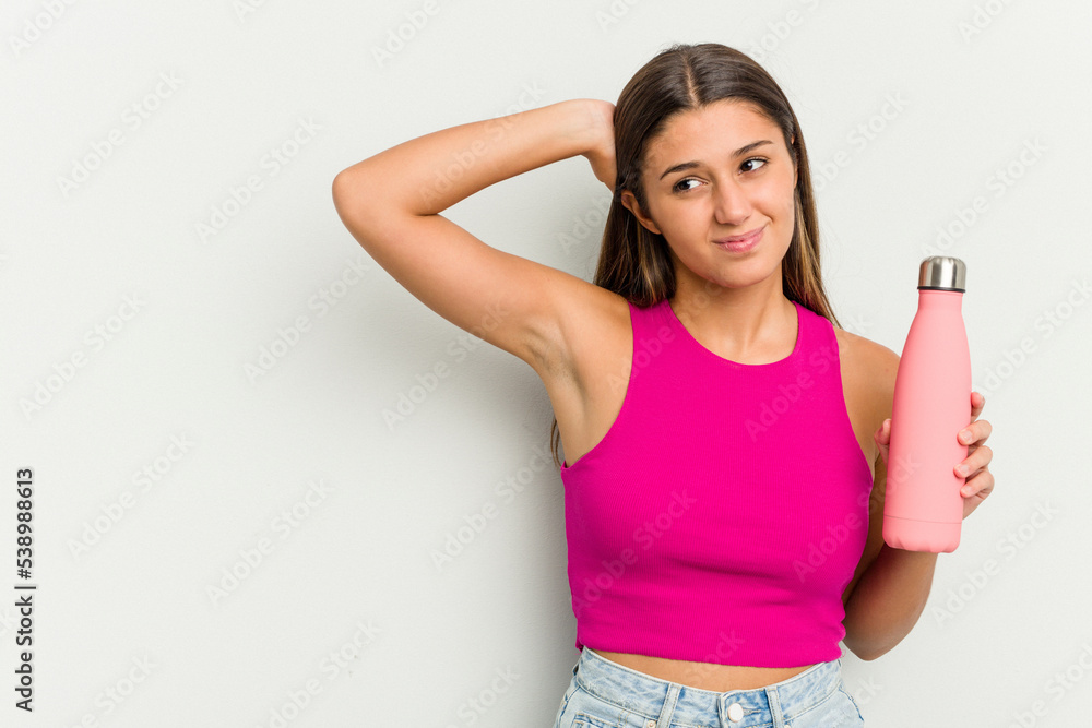 Young indian woman holding a pink thermo isolated on white background touching back of head, thinking and making a choice. Young indian woman holding a pink thermo isolated on white background touching back of head, thinking and making a choice.