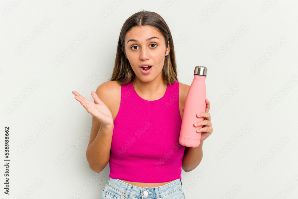 Young indian woman holding a pink thermo isolated on white background surprised and shocked.