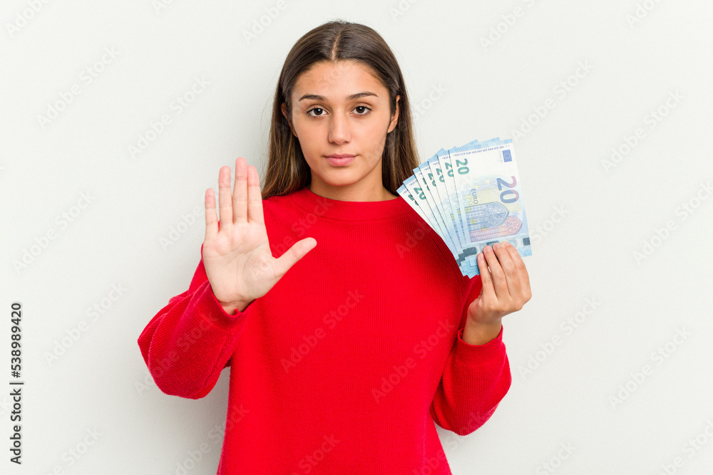 Young Indian woman holding a banknotes isolated on white background standing with outstretched hand showing stop sign, preventing you. Young Indian woman holding a banknotes isolated on white background standing with outstretched hand showing stop sign, preventing you.