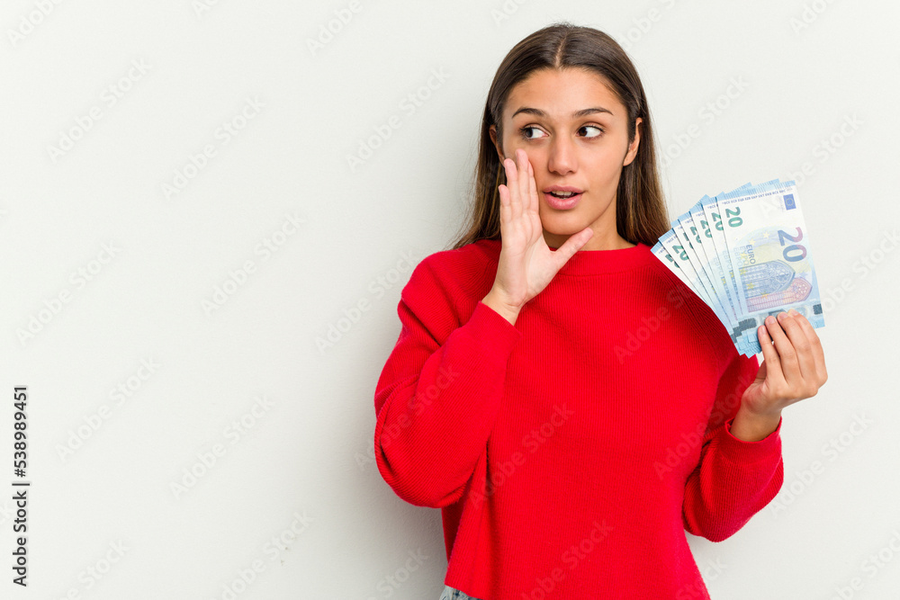Young Indian woman holding a banknotes isolated on white background is saying a secret hot braking news and looking aside Young Indian woman holding a banknotes isolated on white background is saying a secret hot braking news and looking aside