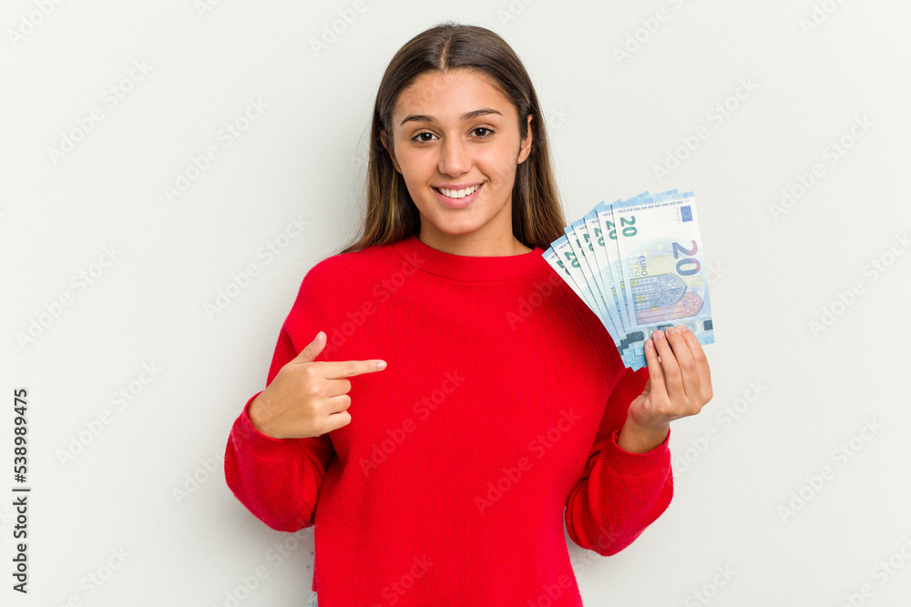 Young Indian woman holding a banknotes isolated on white background person pointing by hand to a shirt copy space, proud and confident