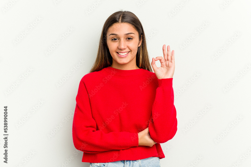 Young Indian woman isolated on white background winks an eye and holds an okay gesture with hand. Young Indian woman isolated on white background winks an eye and holds an okay gesture with hand.