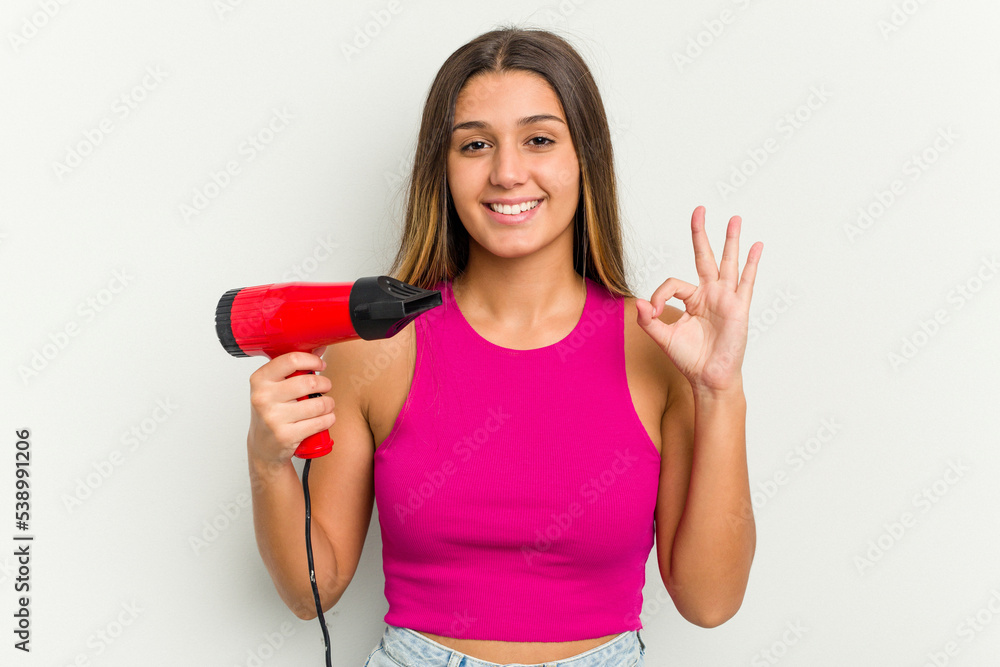 Young Indian woman holding a hairdryer isolated on white background Young Indian woman holding a hairdryer isolated on white background