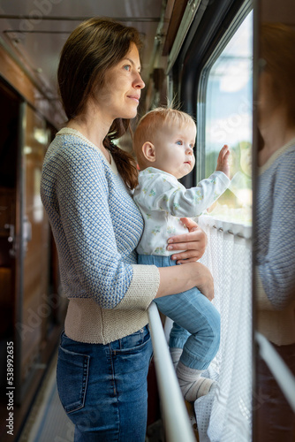Family traveling in a train and looking through window. Woman with child traveling by public transport.