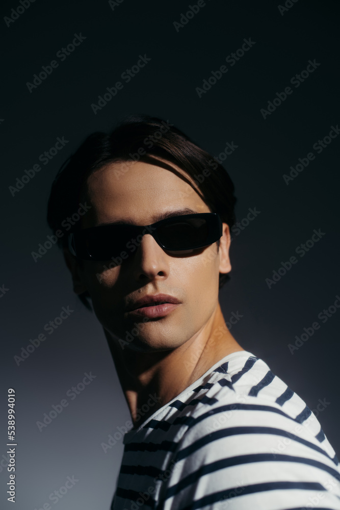Brunette model in sunglasses posing on grey background with lighting Brunette model in sunglasses posing on grey background with lighting