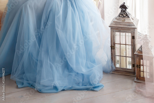 hem of puffy long blue chiffon dress and two lanterns by window