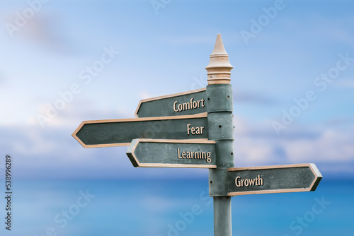 Fotografie comfort fear learning growth four word quote written on fancy steel signpost outdoors by the sea