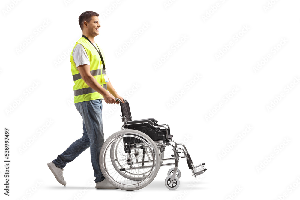 Full length profile shot of a male community worker pushing an empty wheelchair