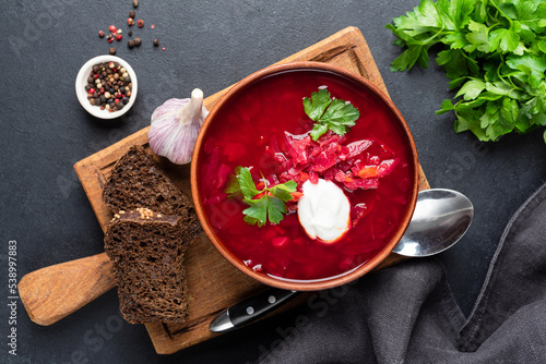 Bowl of ukrainian beetroot soup Borscht served with sour cream and rye bread, table top view