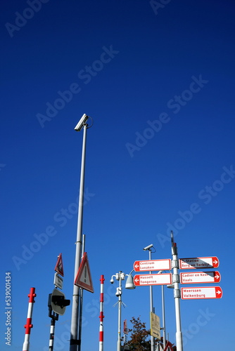 Schranke, Straßenlaterne, Wegweiser und Überwachungstechnik an der Sint Servaasbrug vor blauem Himmel im Sonnenschein in der Altstadt von Maastricht an der Maas in der Provinz Limburg der Niederlande photo