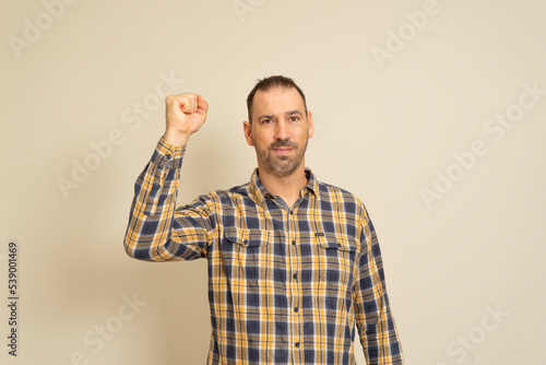 Happy successful bearded businessman winning, fist raised celebrating success isolated beige wall background. Positive human emotion facial expression. Perception of life, achievement.