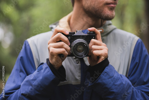 hipster making photo using old vintage camera outdoors