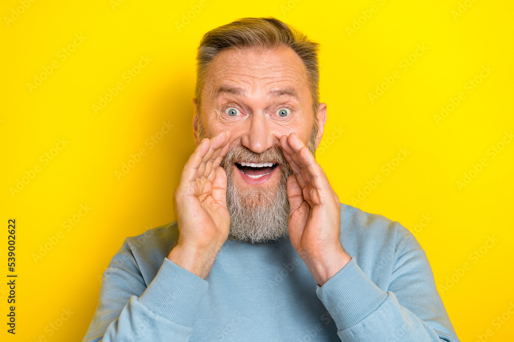 Photo of funky excited retired guy wear blue sweater arms mouth making announcement isolated yellow color background Photo of funky excited retired guy wear blue sweater arms mouth making announcement isolated yellow color background