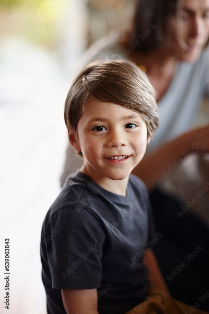 Cant wait till my friends get here. A young boy smiling happily as he sits at home.