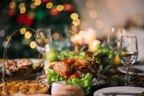 Close up Christmas or Thanksgiving dinner table infront of fireplace and xmas tree decorated at home with blurred bokeh background.