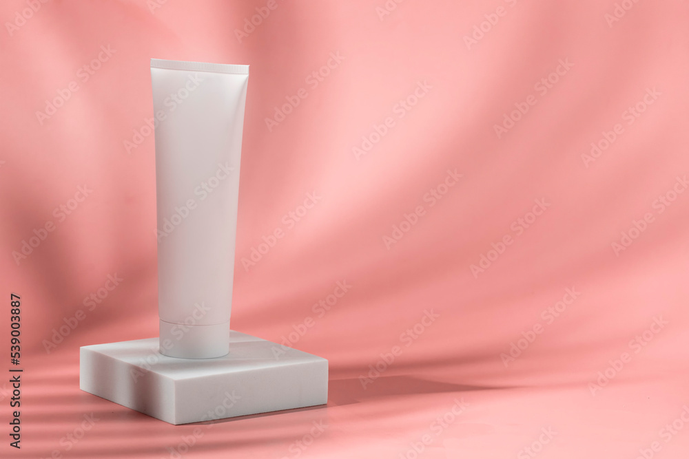 Beauty cocnept. Abstract white cosmetic tube on white podium on pink background with beautiful shadow Beauty cocnept. Abstract white cosmetic tube on white podium on pink background with beautiful shadow