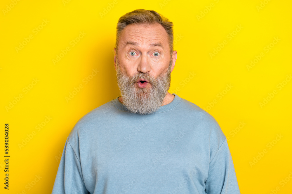 Photo of excited shocked retired guy wear blue sweater big eyes isolated yellow color background Photo of excited shocked retired guy wear blue sweater big eyes isolated yellow color background