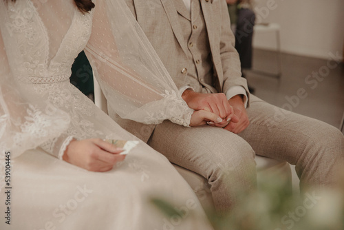Bride and groom holding hands while wedding ceremony photo