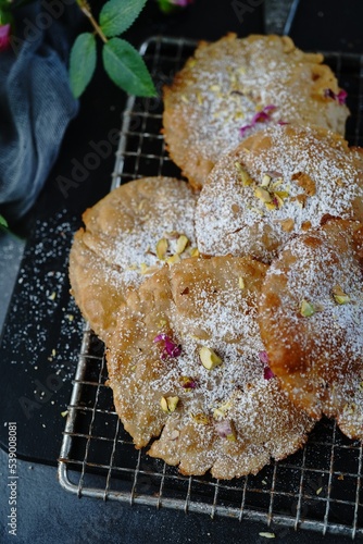 Meethe Chongay or Sweet poori topped with powdered sugar and nuts, selective focus photo