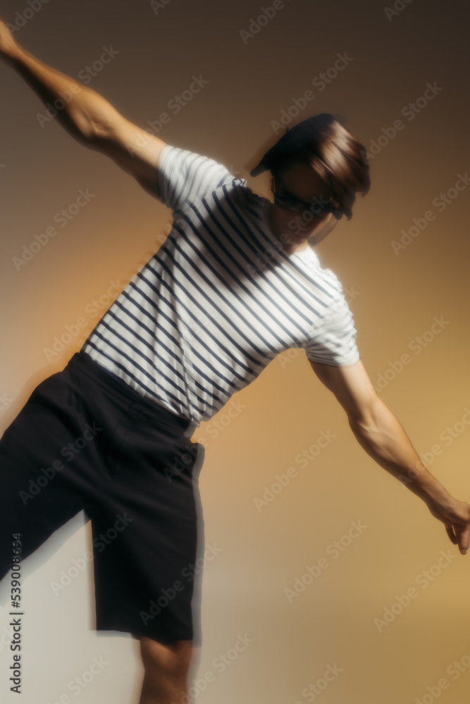 Motion blur of man in striped t-shirt posing on yellow background Motion blur of man in striped t-shirt posing on yellow background