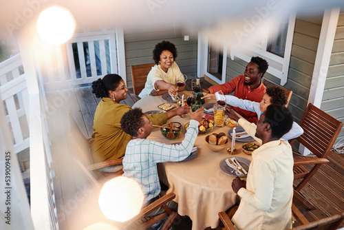 Bild auf Leinwand High angle view at big African American family clinking glasses over dinner tabl