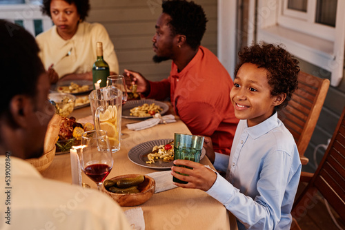 Portrait of smiling African American boy enjoying dinner with family on terrace outdoors