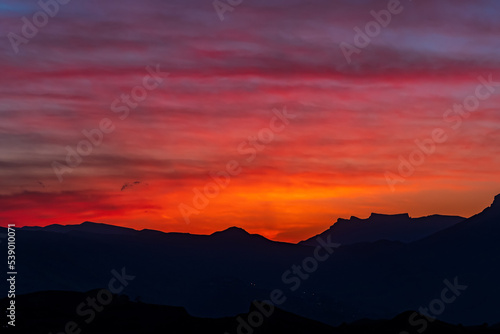 natural background - bright scarlet sunset sky over the silhouettes of mountain peaks