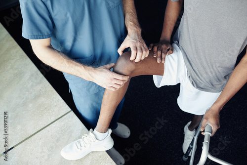 High angle view of doctor making massage of pain leg of athlete after his injury