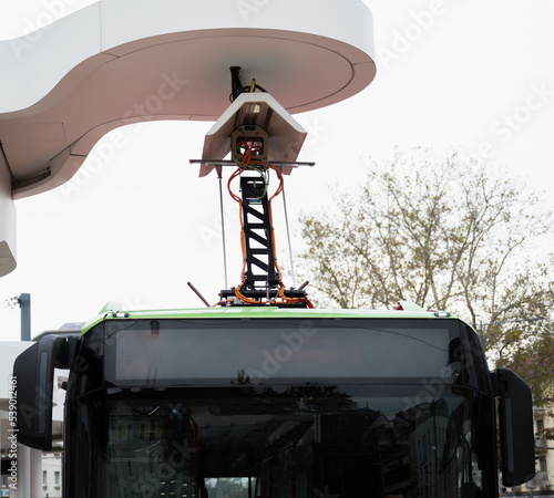 Bus mit innovativem Stromabnehmer an Ladestation an Haltestelle. Elektrischen Strom laden an Pantograph