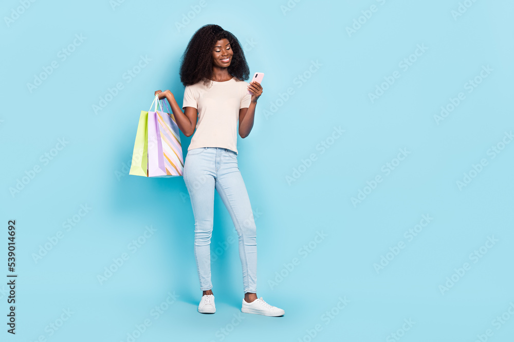 Full size portrait of pretty attractive person hold packages use telephone isolated on blue color background Full size portrait of pretty attractive person hold packages use telephone isolated on blue color background