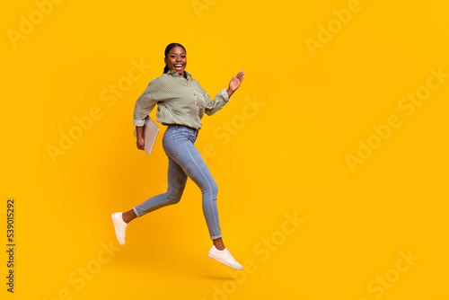 Full size profile photo of cheerful lady hold netbook rush hurry meeting isolated on yellow color background