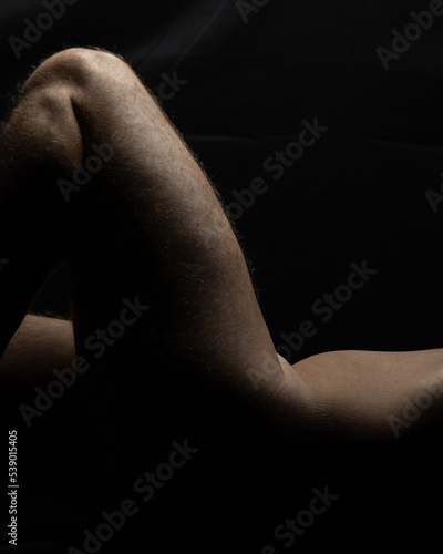 closeup of sensual nude male fitness model with focus on bare torso and legs