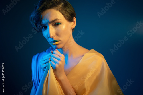 young ukrainian woman in yellow and blue clothes and dress praying for ukraine photo