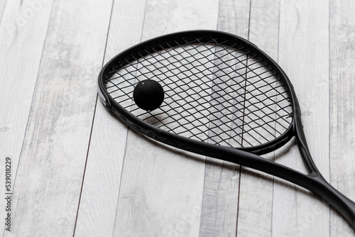 Black squash racket and ball on grey court. Horizontal sport theme poster, greeting cards, headers, website and app © Augustas Cetkauskas