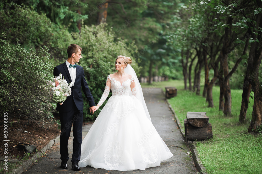 Happy wedding couple walking in a botanical park