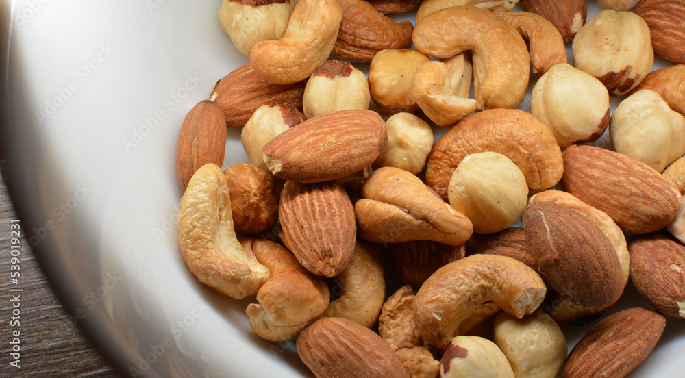Healthy snack: Close up photo of roasted cashews, almonds and hazelnuts in a white bowl. Healthy snack: Close up photo of roasted cashews, almonds and hazelnuts in a white bowl.