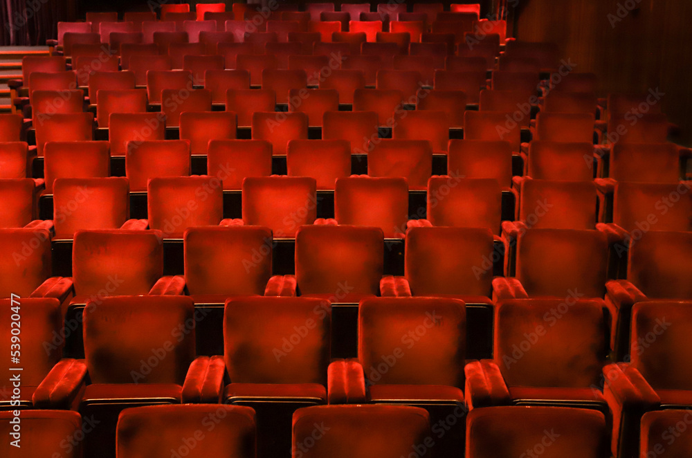 Red velvet chairs in a theater, highlighting the symmetry, lines and