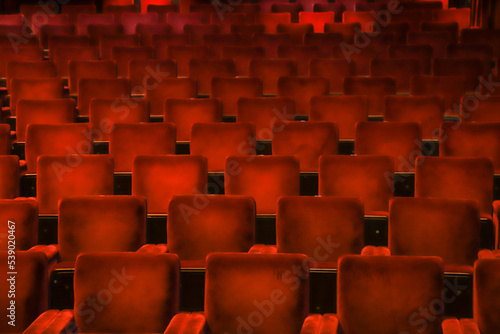 Red velvet chairs in a theater, highlighting the symmetry, lines and repetition of the seats.
