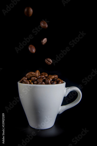 White cup with coffee beans on a black background