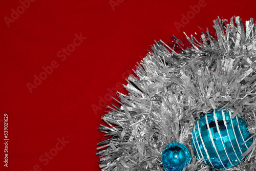Fondo rojo con guirnaldas plateadas y bolas de navidad azules.
 photo