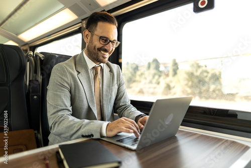 Young business man traveling to work by train.  Working while traveling, using laptop, mobile phone and notebook Thinking about new goals, noting, planning work © Nemanja