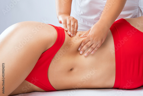 The masseur makes a massage on the abdomen, waist and hips in the spa. Overweight treatment, body sculpture. The concept of cosmetology and massage. © Dimid