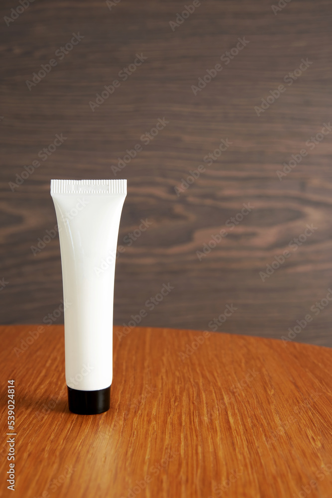 White cosmetic plastic tube with cream on the wooden table White cosmetic plastic tube with cream on the wooden table