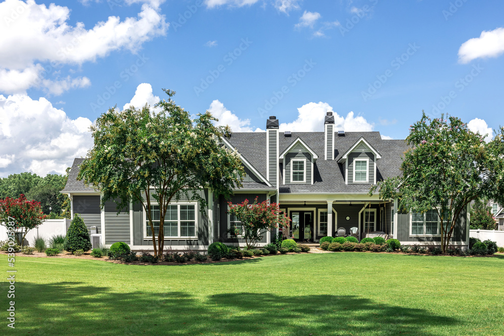 © Ursula Page - The rear view of a large gray craftsman new construction house with a landscaped yard and a garage and driveway
