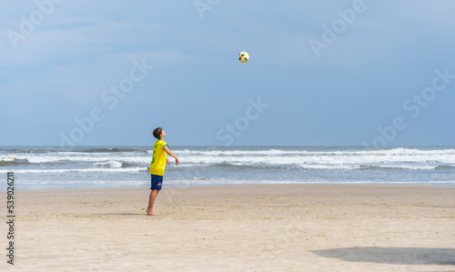 garoto jogando futebol na praia sozinho  photo