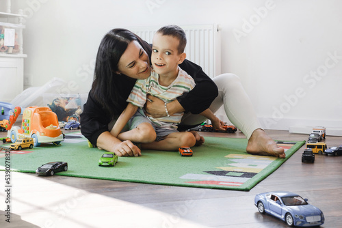 Obraz na plátne Kid with health problem playing toy cars with mother at home