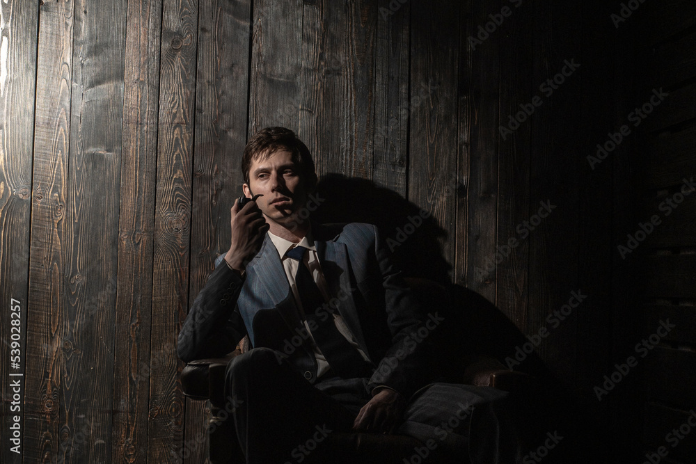 thoughtful man is sitting in an armchair and smoking a pipe, a portrait in semi-darkness with dark shadows, vintage noir style thoughtful man is sitting in an armchair and smoking a pipe, a portrait in semi-darkness with dark shadows, vintage noir style